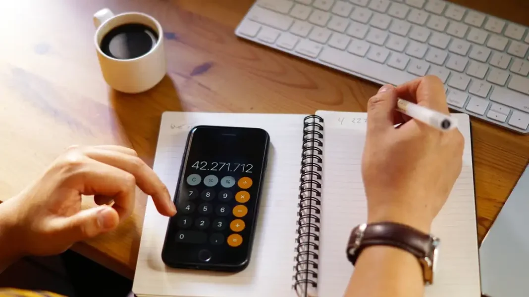 Celular e caderno para organizar informações financeiras de uma empresa